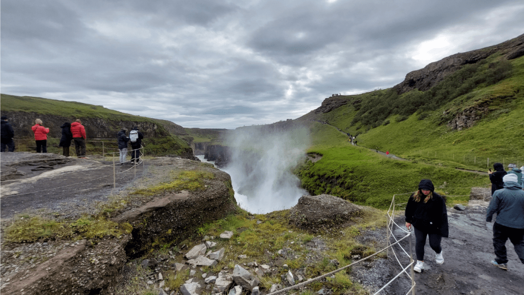 davanti a una cascata islandese con giacca impermeabile